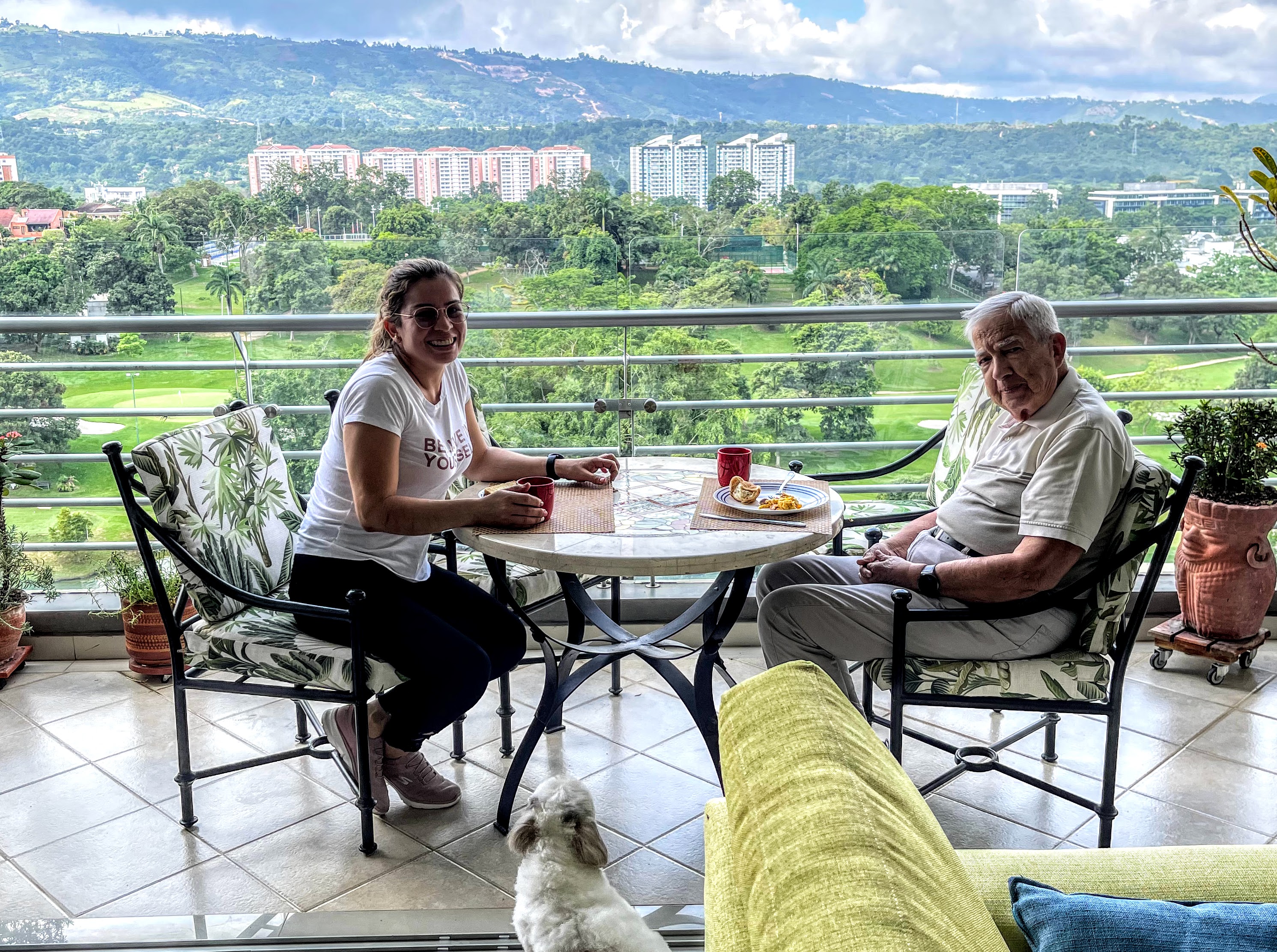 Retiree and maid sitting down to breakfast on the terrace with a view of the Andes in the background.